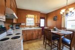 The full size kitchen with dining table is stocked with cookware, dishes, and utensils.